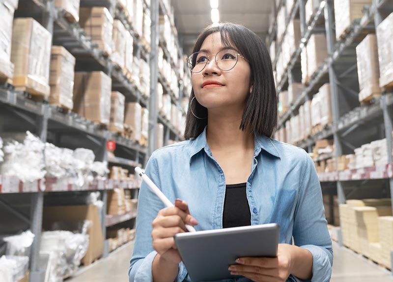 employee writing on clipboard looking up in warehouse
