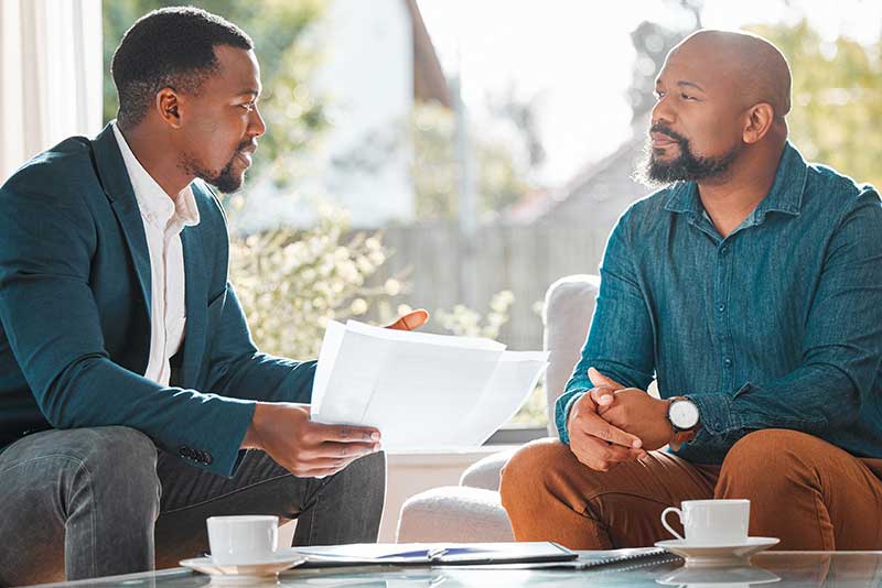 two men talking and holding papers